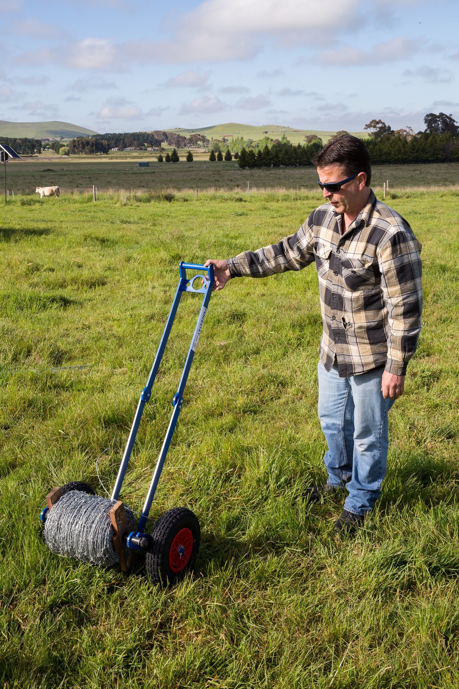 Farmer rolling out wire fencing in paddock